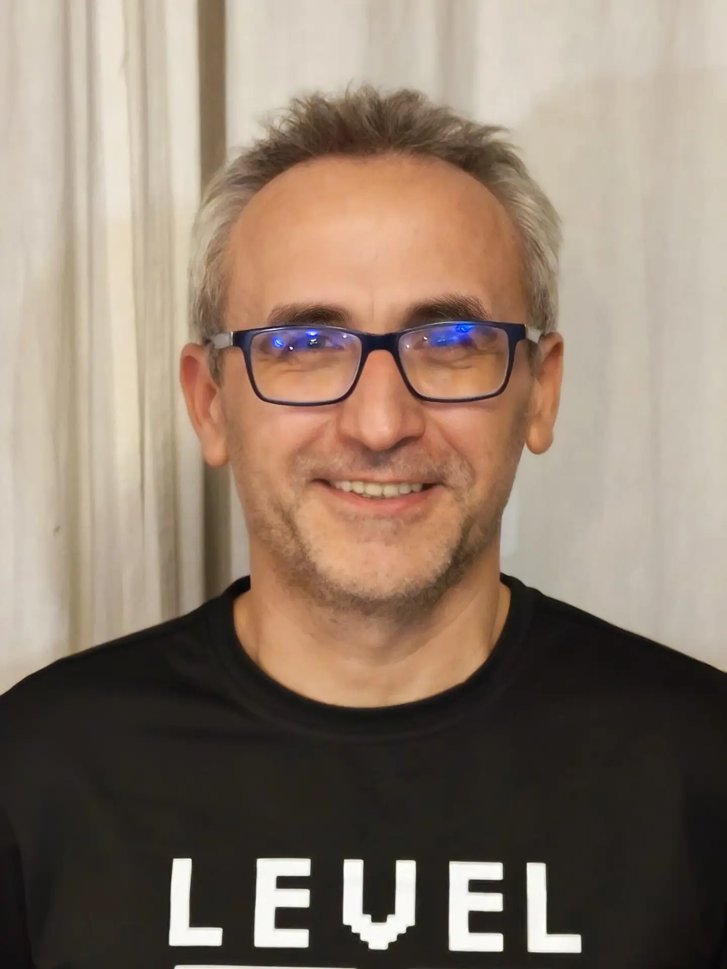 Robert Conduruta - instructor SSI, fotografiată într-o fotografie portret casual. Poartă ochelari și un tricou negru cu inscripția „LEVEL” într-un stil retro pixelat. Imaginea transmite un sentiment de accesibilitate și profesionalism.