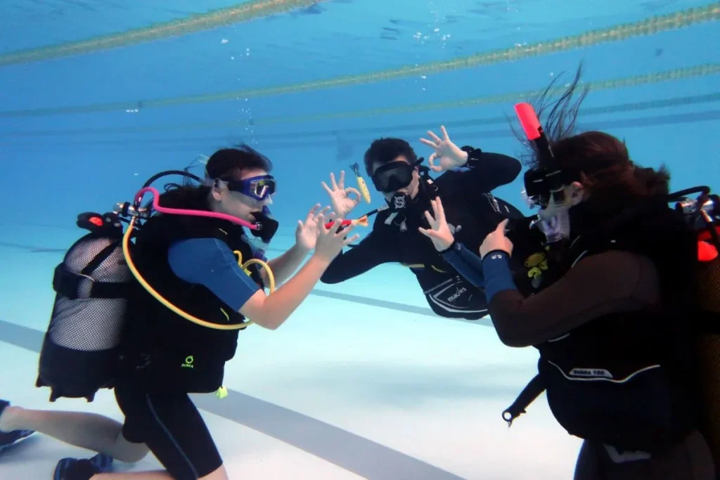 Cursanți Try Scuba exersând semnale de comunicare sub apă, în echipă