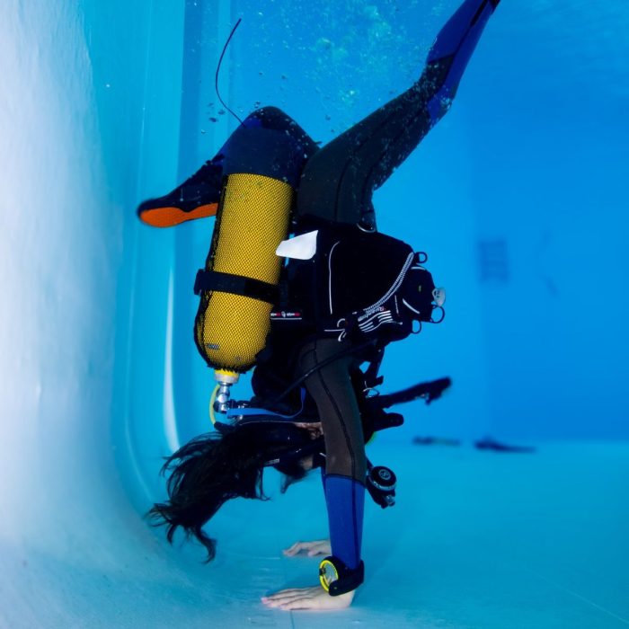 Scafandru executând o poziție pe cap sub apă, demonstrând abilități avansate de control al flotabilității în cadrul unui curs Deep Zone Diving.