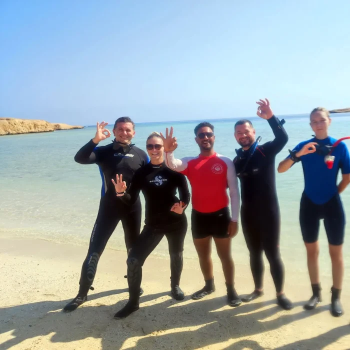 Cinci scafandri în costume de neopren, semnaland OK, pregatiți de scufundare pe plaja Marsa Alam.
