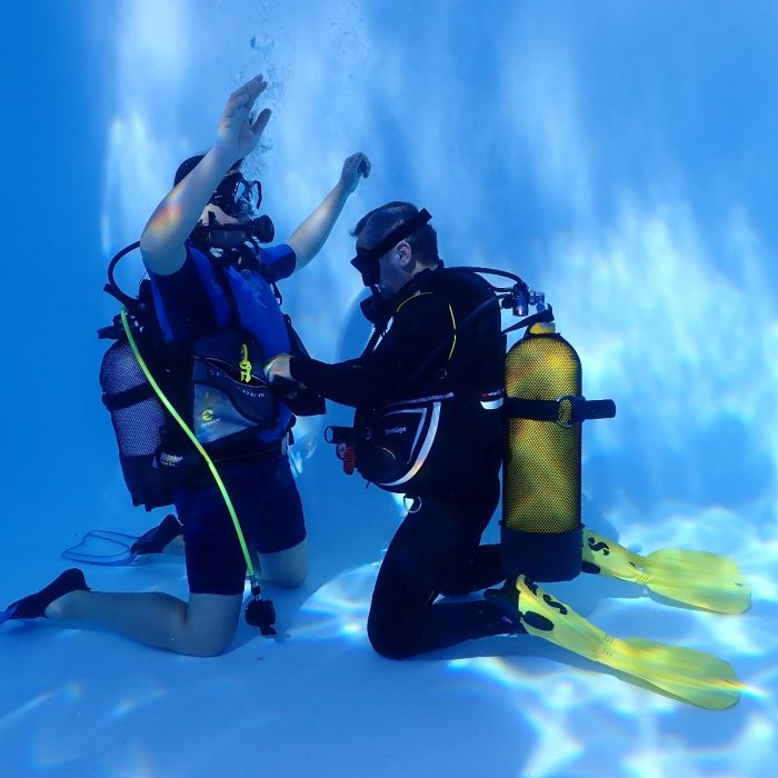 Instructor SSI ajuta cursantul in timpul unei lectii practice de scufundari in piscina
