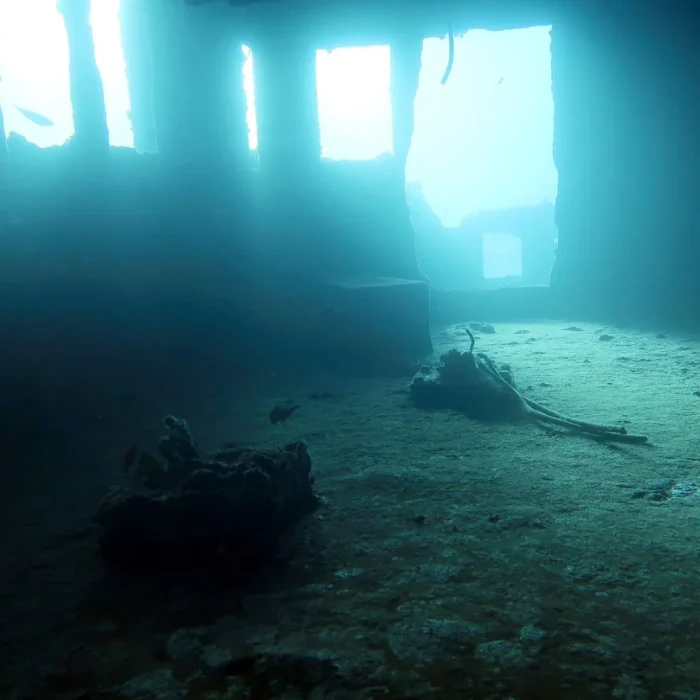 Interiorul unei epave scufundate luminat de razele soarelui filtrate prin apă, perfect pentru scufundări de explorare.