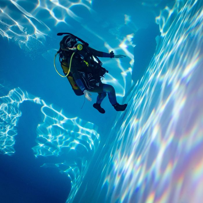 Scafandru plutind intr-o piscina iluminata spectaculos, in timpul unei sesiuni de scufundari cu Deep Zone Diving.