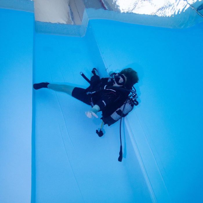 Scafandru așezat pe fundul piscinei, într-o poziție relaxată, văzut de sus în timpul unui antrenament Deep Zone Diving