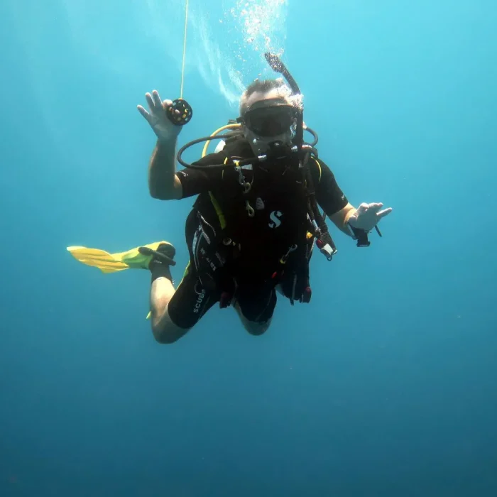 Scafandru cu boy galben de semnalizare plutind la adâncime în cadrul unei scufundări Deep Zone Diving