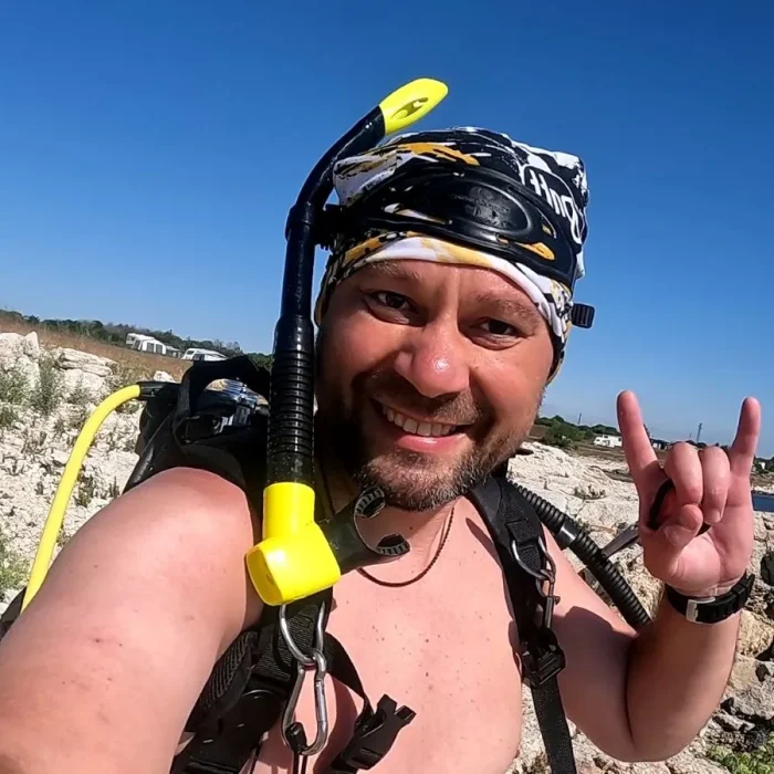 Scafandru zâmbitor pregătit pentru scufundare alături de Deep Zone Diving, pe țărm stâncos