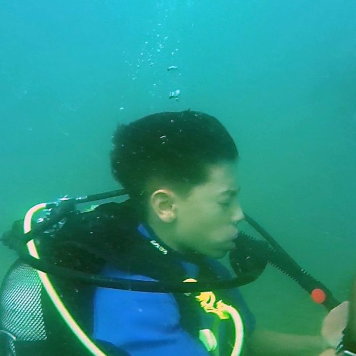 Copil participa la o sesiune de scufundare in apa deschisa alaturi de instructor