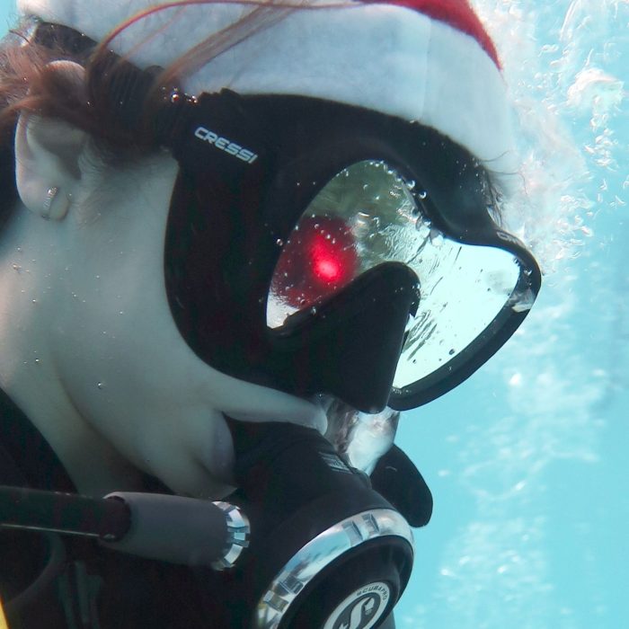 Prim-plan cu un scafandru care poarta masca de scufundare si caciula de Mos Craciun, in timpul unei sesiuni festive organizate de Deep Zone Diving.