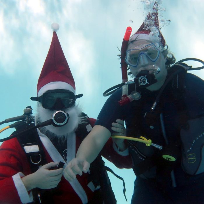 Santa Claus scafandru alaturi de un coleg in costum de scufundare, pregatiti de o aventura subacvatica de Craciun.