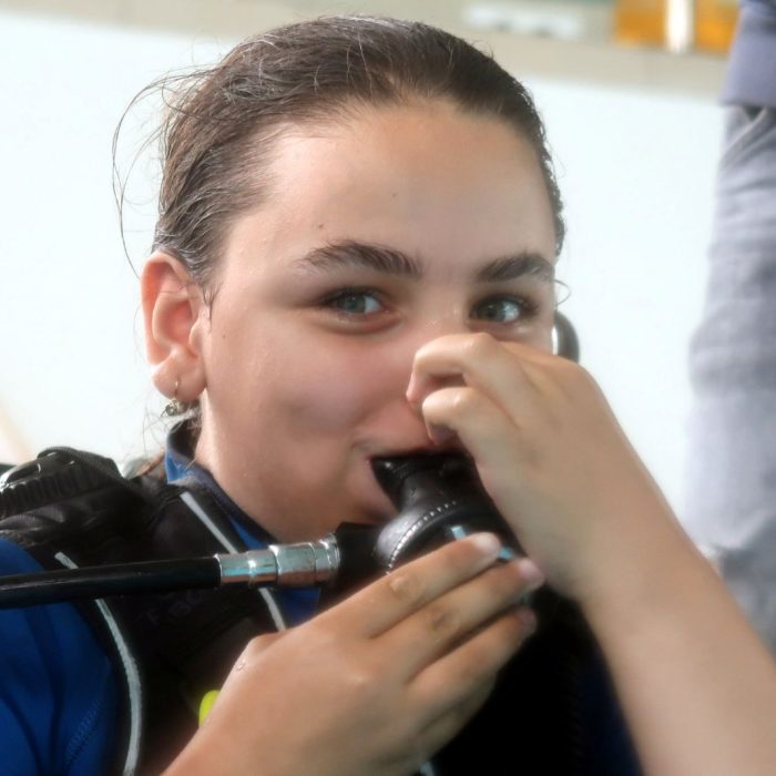 Fata zambitoare testeaza respiratia prin regulatorul de scufundare, in cadrul sesiunii introductive a cursului Try Scuba organizat de Deep Zone Diving.